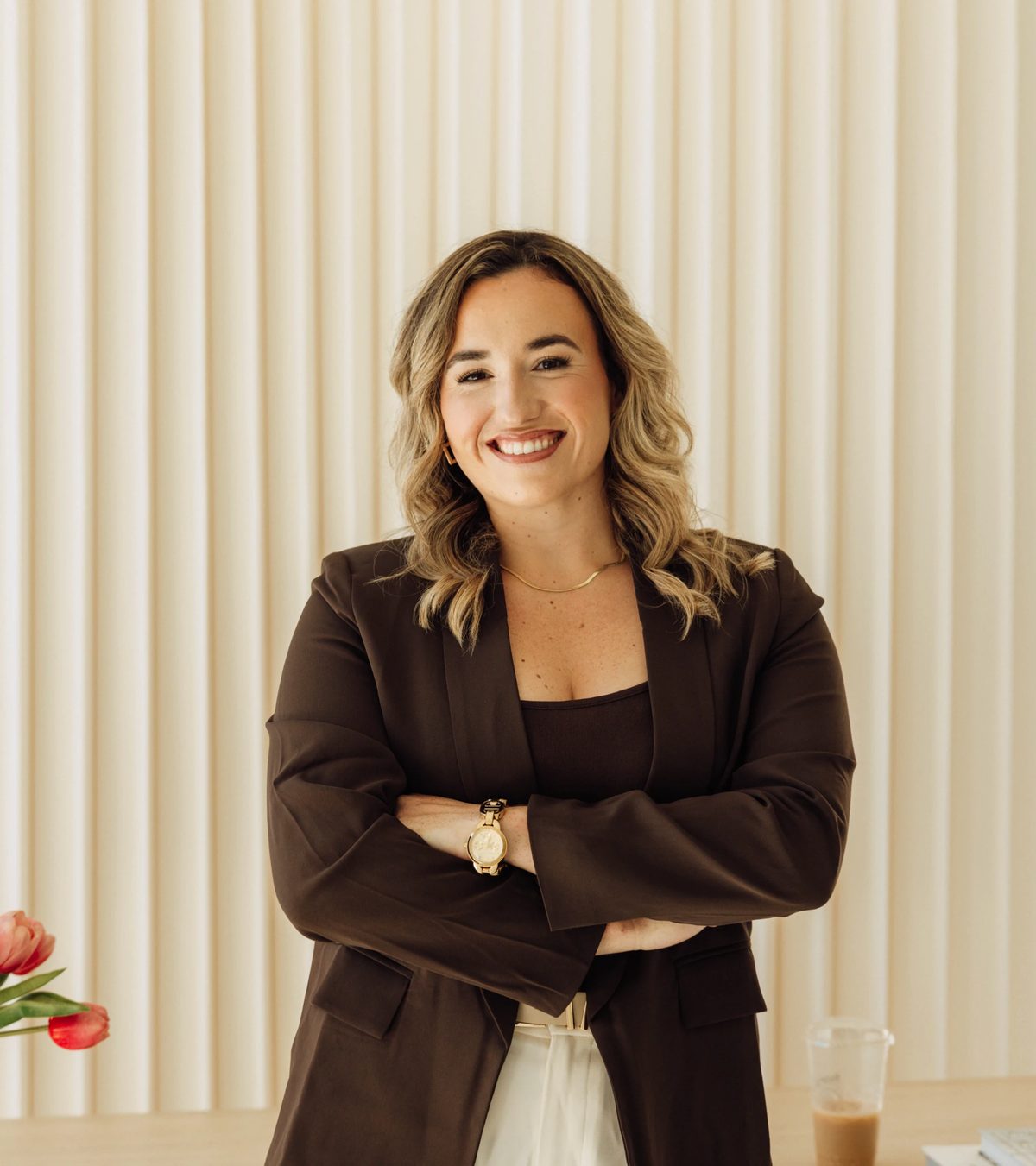 Kristin Pitts, founder of Aligned Consulting, standing with her arms folded in front of cream curtains